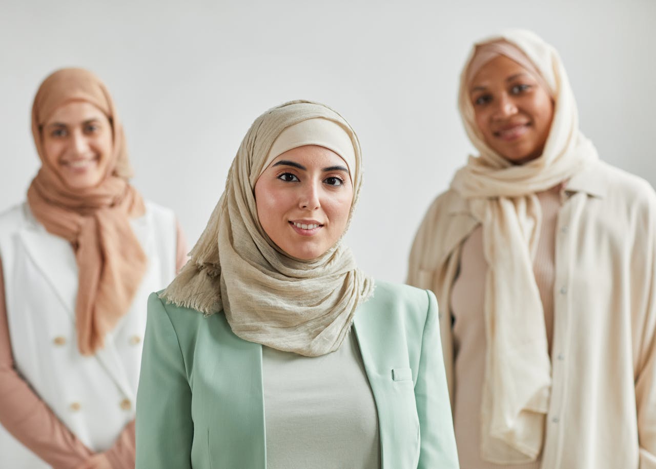 Portrait of three diverse women in hijabs smiling, symbolizing unity and cultural diversity.